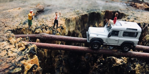 Lego figures acting out a dangerous tree-trunk-bridge crossing by a jeep