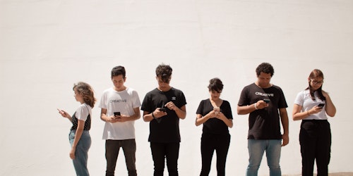 A line of teenagers looking at their phones
