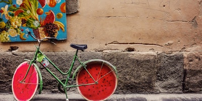 A customized bicycle, made to look like a watermelon, in a colorful setting