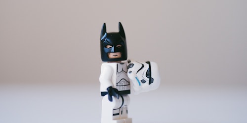 A storm trooper Lego figure, having revealed their helmet to reveal Batman's cowl