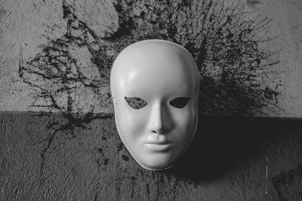A white dramatic mask on a concrete background