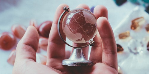 A tiny glass globe, held in the palm of a hand