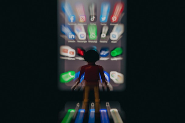 A lego man in front of a phone, showing a wall of apps, in a dreadful blur