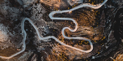 A winding road leading through a mountain, seen from above