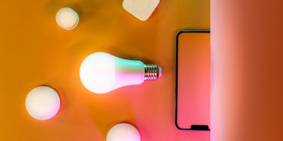 Lightbulbs and a mobile phone on an orange background