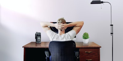 A remote worker kicking back with their hands on their head