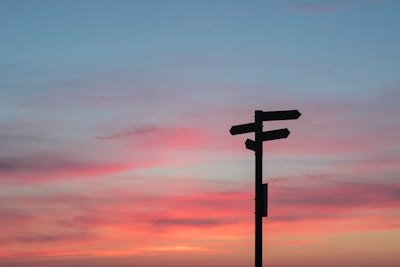 A wooden signpost against a gradient sunset