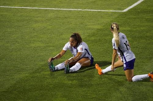 Two women soccer players warming up on the pitch