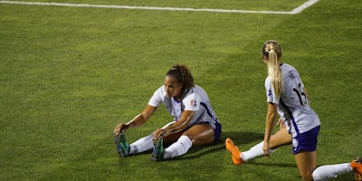 Two women soccer players warming up on the pitch