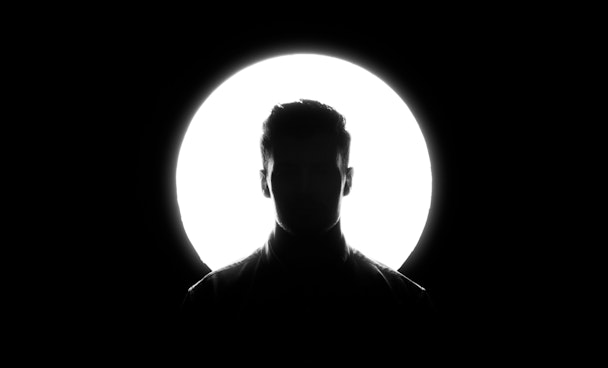 A person's head in silhouette against a round spotlight