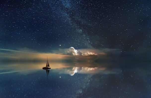 A sail boat at sea, among reflected stars