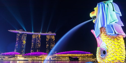 A neon-lit nighttime view of Singapore's iconic marina