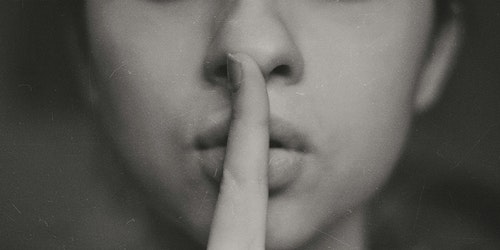 A pair of human lips, with a finger to them in a 'shh' gesture