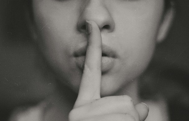 A pair of human lips, with a finger to them in a 'shh' gesture