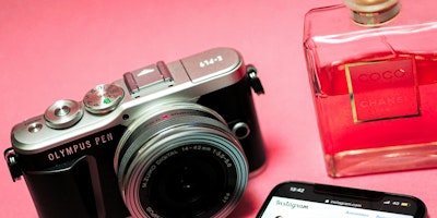 A camera, a perfume bottle, and a smartphone on a pink background
