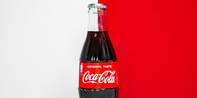 A  bottle of Coca-Cola, against a red and white background