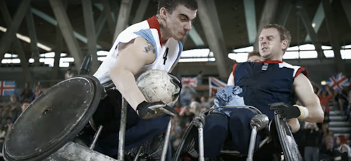Two atheletes using wheelchairs playing basketball