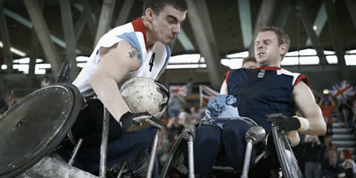Two atheletes using wheelchairs playing basketball