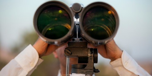A person looking into a large pair of binoculars