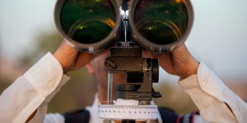 A person looking into a large pair of binoculars