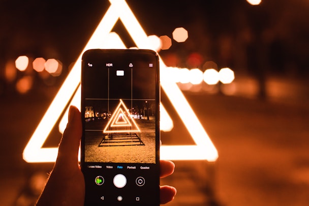 A phone, on a tripod, capturing an image of a triangular light display
