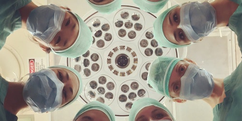 A ring of doctors looking down on a presumed patient