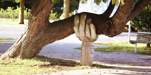 A tree, carved to look like a hand, "supporting" another tree