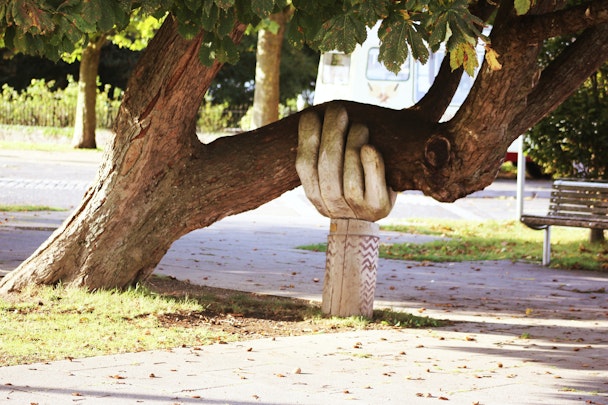 A tree, carved to look like a hand, "supporting" another tree