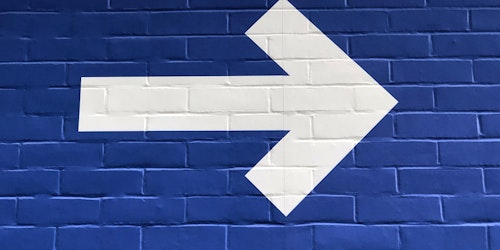 A white arrow painted on a blue wall