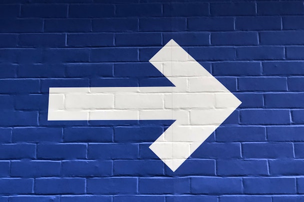 A white arrow painted on a blue wall