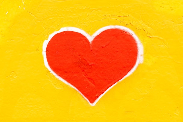 Graffiti of a red heart on a yellow wall