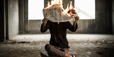 A person reading a newspaper that is on fire