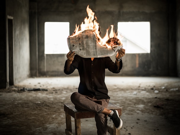 A person reading a newspaper that is on fire