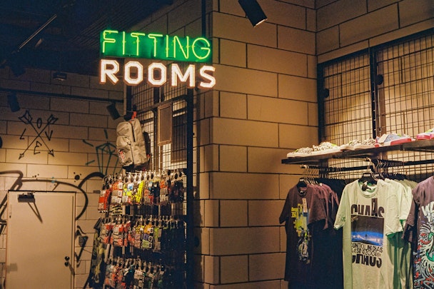 A fitting room in a clothes shop with a neon sign