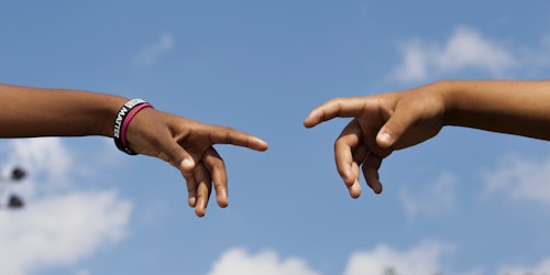 Two young people's hands reaching out, in an imitation of Michelangelo's The Creation of Adam