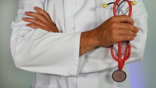 A doctor's arms, holding a stethoscope 