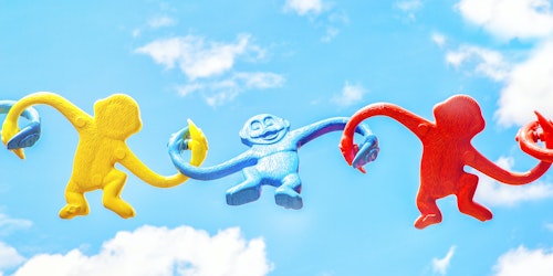 Three primary-color plastic monkeys, held aloft to the sky, holding hands, full of joy