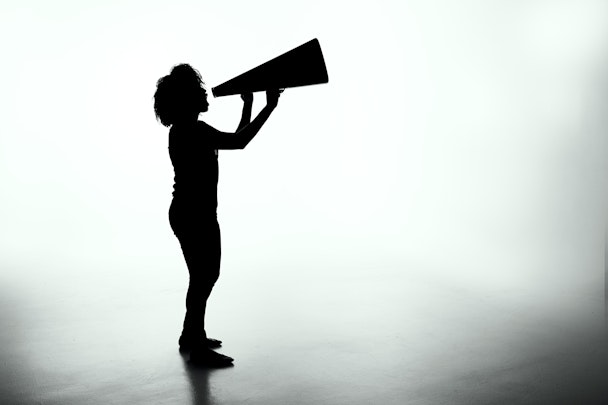 A person in silhouette shouting into a loudspeaker