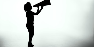 A person in silhouette shouting into a loudspeaker