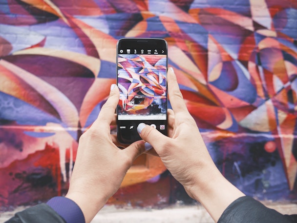 A pair of hands taking a picture of a street art mural