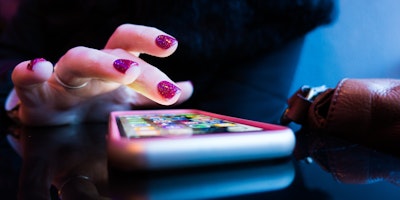A person's hand hovering over a lit-up smart phone