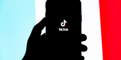 A hand holding a phone featuring the TikTok app