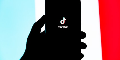 A hand holding a phone featuring the TikTok app