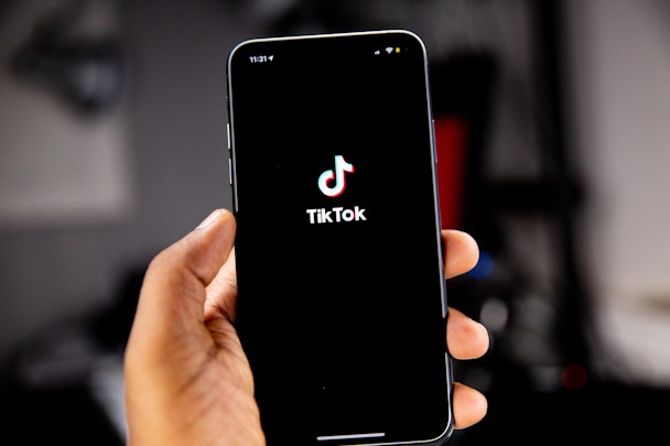 A hand holding a phone, with the TikTok app open