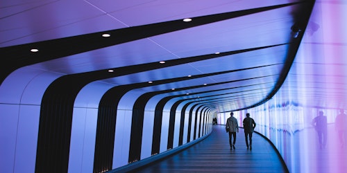 Two people walking down a futuristic-looking hallway