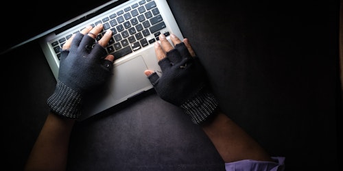 Hands in fingerless gloves typing on a laptop