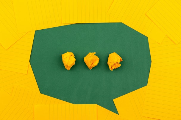 A green speech icon on a yellow background, made of paper