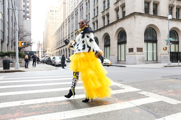 A stylish woman in yellow clothes crossing a New York street