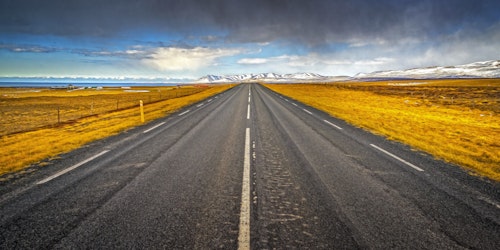 A prairie road leading to a mountain range