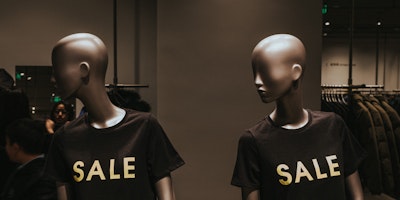 Two mannequins wearing 'SALE' shirts